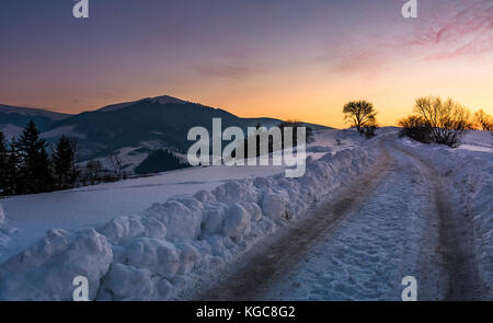 Landschaft Straße bergauf im Schnee bei Sonnenuntergang. schöne Winterlandschaft im Berggebiet Stockfoto