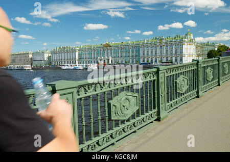 Mann auf einer Brücke über den Fluss. in seiner Hand eine Flasche Wasser aus Durst. Stockfoto