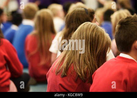 Gruppe der Schulkinder sitzen in der Montage in einer britischen Grundschule Stockfoto