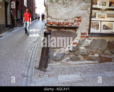 STRASSENECKE´s Stockholms Altstadt, die seit Jahrhunderten mit einer alten Kanone und einem Runenstein gemacht ist Stockfoto