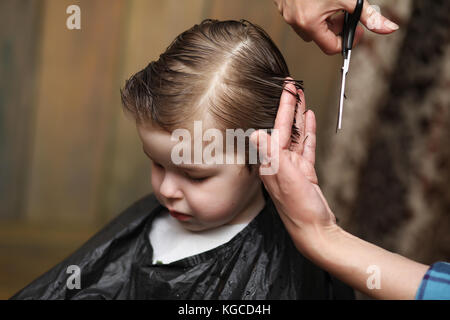 Ein kleiner Junge ist in hellen die Emotionen der Friseur auf getrimmt Stockfoto