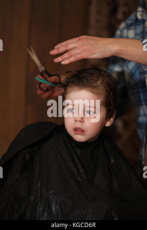 Ein kleiner Junge ist in hellen die Emotionen der Friseur auf getrimmt Stockfoto