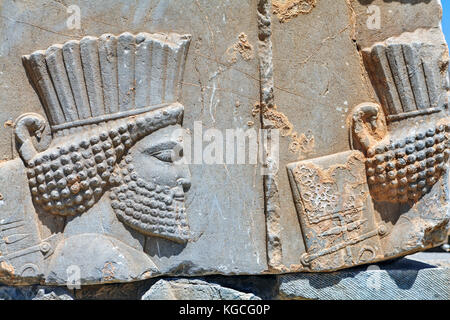 Ein Basrelief mit der Darstellung eines Kriegers in Irans berühmtesten Touristen vor Ort, ein Open-Air-Museum der antiken persischen Stadt Persepolis, nicht weit her entfernt Stockfoto