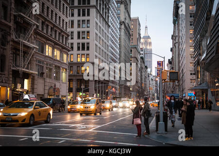 Midtown Manhattan am Abend, den 19. März 2016. Die Menschen warten, die Straße zu überqueren, wie Yellow Cabs Antrieb durch. Stockfoto