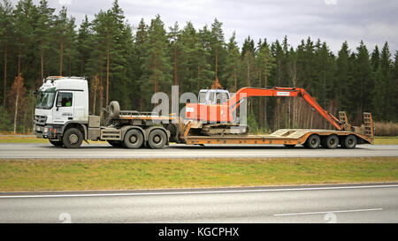 Paimio, Finnland - 30. Oktober 2015: weiße Mercedes-Benz Actros hols Hitachi ex 60 Bagger Hitachi EX60 ist ein MIDI-Bagger mit max Aushubreichweite o Stockfoto