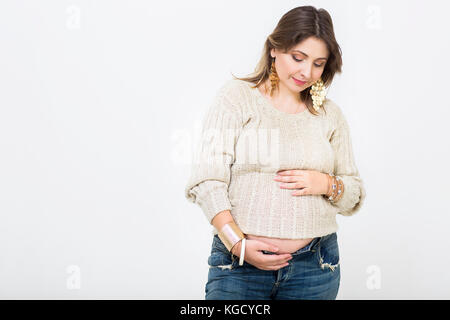 Junge hübsche schwangere Frau in Freizeitkleidung im Studio Stockfoto