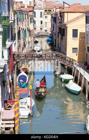 Gondoliere rudern seine Gondel mit Touristen in Rio Priuli, Cannaregio, Venice, Italien, einem malerischen Kanal zurück. Hohe Blickwinkel betrachten. Stockfoto