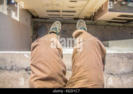 Mann sitzt auf einer Leiste auf einem hohen Gebäude. Stockfoto