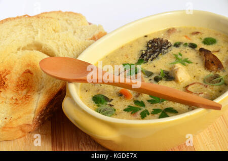 Cremesuppe zubereitet von Hühnerfleisch und viele Sorten von Pilzen, mit frischen, grünen Kräutern Gewürzen gewürzt und im rustikalen, Keramik Schüssel serviert mit t Stockfoto