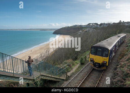 Oktober 2017, ein Tourist macht ein Foto von Carbis Bay in Cornwall als eine Great Western Railway Zug fährt vorbei im Hintergrund Stockfoto