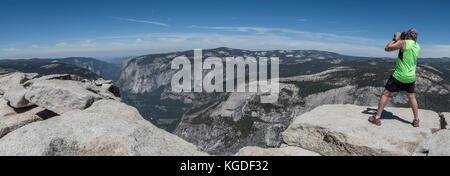 Ein Mann nimmt Fotos von der Kante auf der Oberseite des Half Dome im Yosemite National Park. Stockfoto