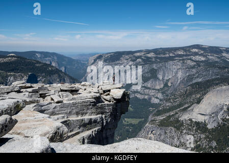 Ein Mann steht triumphierend auf der Oberseite des Half Dome mit Yosemite Valley in den Hintergrund in Yosemite National Park. Stockfoto