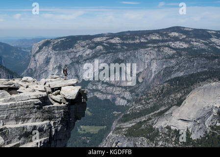 Ein Mann steht triumphierend auf der Oberseite des Half Dome mit Yosemite Valley in den Hintergrund in Yosemite National Park. Stockfoto