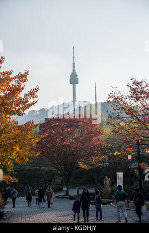 Herbstfarbene Bäume mit koreanischen Menschen im Vordergrund und Blick auf den Seoul N Tower im Hintergrund Stockfoto