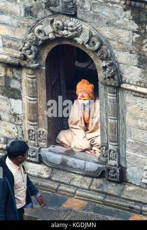 Nepalesischen Mann vorbei vor einer hinduistischen Sadhus in einem Schrein sitzt, heiliger Mann, Pashupatinath Tempel, Kathmandu, Nepal Stockfoto