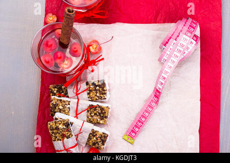 Diät Müsliriegel mit detox Apfel-zimt-Wasser und Maßband auf rote Paprika und Holz- Hintergrund. Ansicht von oben. Flach Stockfoto