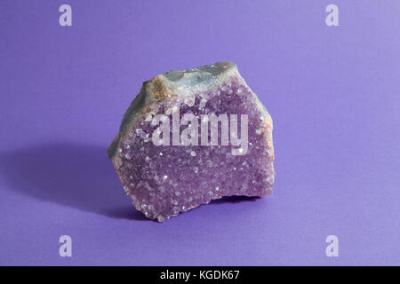 Amethyst Druse, der auf einer lebhaften Pop lila Hintergrund. Minimale still life Fotografie Stockfoto