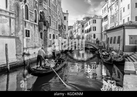 Schöner Blick auf eine typisch venetianische Gondel in einem zentralen Kanal, Venedig, Italien, in Schwarz-Weiß Stockfoto