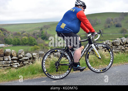 Übergewicht Radfahrer Radfahren bergauf in Yorkshire, Großbritannien Stockfoto