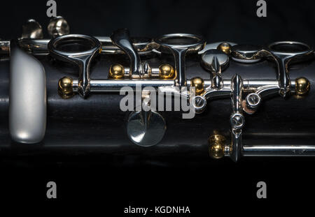 Details einer Klarinette mit silbernen und goldenen Buchsen schwarzer Hintergrund Stockfoto