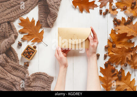 Valentinstag Thema. Blick von oben auf die weibliche Hände setzen Gruß Brief im Umschlag. Lügen Rosen und Herz aus Papier auf die schäbigen Holztisch. Stockfoto