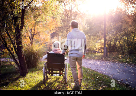 Älterer Mann und Frau im Rollstuhl im Herbst Natur. Stockfoto