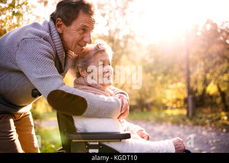 Älterer Mann und Frau im Rollstuhl im Herbst Natur. Stockfoto