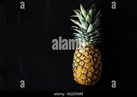 Reif ganze Ananas auf einen schwarzen Stein Hintergrund. Kopieren Sie Platz Stockfoto