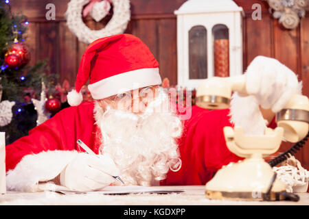 Santa Claus auf das Telefon an seinem Haus stellt die Wunschzettel für Weihnachten Stockfoto