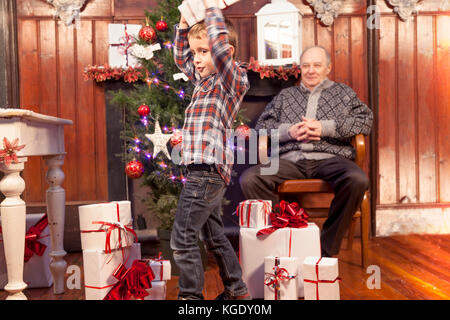 Adorable Little Boy gibt ein Weihnachtsgeschenk zu seinem Großvater Stockfoto