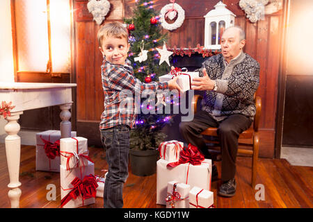 Adorable Little Boy gibt ein Weihnachtsgeschenk zu seinem Großvater Stockfoto