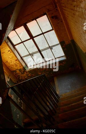 Das alte Lagerhaus blickt von der Treppe runter und aus dem schmutzigen Fenster Stockfoto