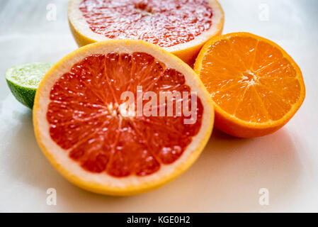 Bunte halbe Zitrusfrucht, Seitenansicht, Nahaufnahme. Grapefruit, Orange und Limone Früchte Hälften, Makro, horizontal. Stockfoto