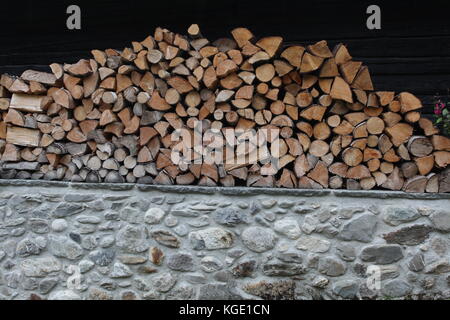 Protokolle von Holz gehackt und für den Winter eingelagert als burnging Material, auf einer Steinmauer, in Europa platziert. Stockfoto