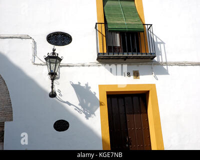 Schatten von aufwendigen Laterne weiß gestrichenen Wand mit Fensterläden in Sevilla, Spanien Haus Nummer 18. Stockfoto