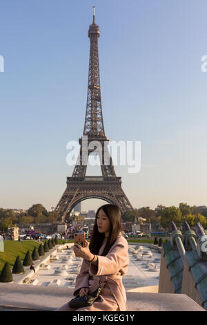 Asiatische Frau touristische nimmt selfie mit Handy vor der ikonischen Wahrzeichen Eiffelturm Paris Stockfoto