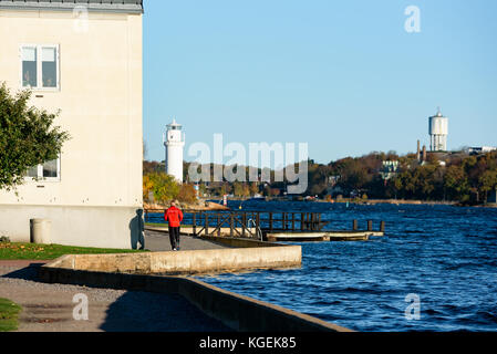 Karlskrona, Schweden - 30. Oktober 2017: Dokumentation des Alltags und der Umwelt. Mann, der am Morgen in der Sonne entlang der Küste in der Stadt läuft Stockfoto