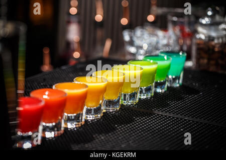 Eine Reihe von harten alkoholischen Schüsse in Regenbogenfarben serviert auf der Theke Stockfoto