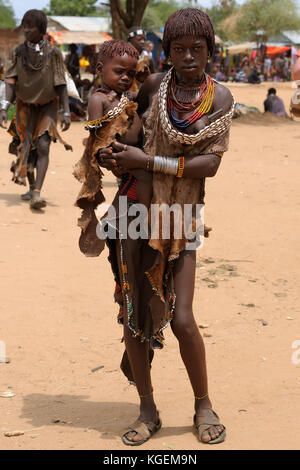 Turmi, omo Valley, Äthiopien - Juli 29: Porträt der jungen Mädchen mit dem Kind auf Händen von Hamer Menschen ruhen unter dem Baum in Transit Stockfoto