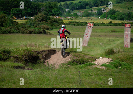 Motorcross-Fahrer auf der Ziellinie eines Cross-Trails, der seine Fähigkeiten in schwierigem Gelände demonstriert Stockfoto