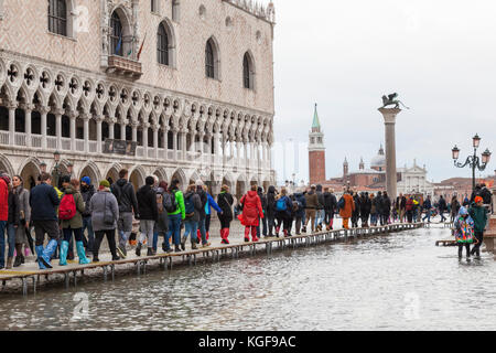 Venedig, Venetien, Italien. 7 Nov, 2017. Acqua Alta Flut von 115 cm von der Lagune verursacht temporäre Überflutungen in der Piazza San Marco. Passarelle oder erhöhte Gehwege, sind für die Fußgänger mit einer langen Reihe von Menschen zu Fuß in Richtung der Lagune hinter dem Dogenpalast installiert. Credit: Mary Clarke/Alamy leben Nachrichten Stockfoto