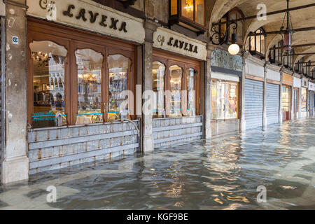 Venedig, Venetien, Italien. 7 Nov, 2017. Acqua Alta Flut von 115 cm von der Lagune verursacht temporäre Überflutungen in der Piazza San Marco. Die geschlossene Räumlichkeiten der Caffè Lavena mit Metall Wasser Schranken und den Schlauch einer Wasserpumpe. Auf dem Fenster markiert ist, um die Flut Marke oder Wasserstand der devestating Acqua Alta Flut 1966. Credit: Mary Clarke/Alamy leben Nachrichten Stockfoto