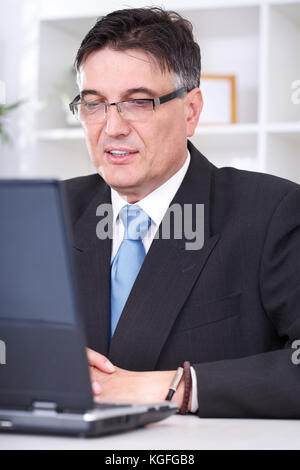Porträt eines lächelnden erfolgreicher Geschäftsmann mit einem Laptop bei der Arbeit im Büro Stockfoto