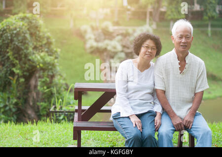 Gerne asiatische älteres Paar sitzt auf der Bank im Sommer Park. Stockfoto