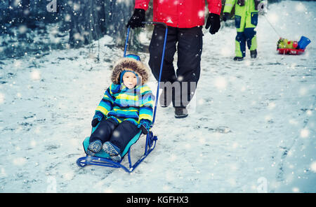 Vater mit Söhnen gehen bei Schneefall Stockfoto