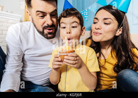 Happy Family ausblasen Kerze zum Geburtstag muffin zusammen Stockfoto