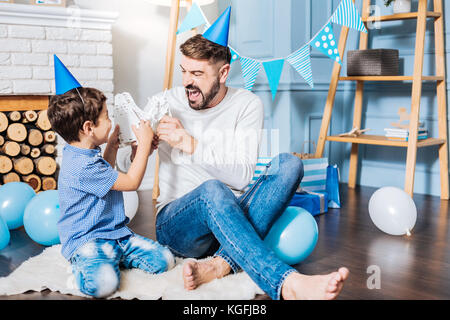 Fröhlicher Mann und sein Sohn spielen mit Spielzeug Roboter Stockfoto