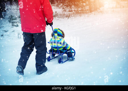 Vater mit Söhnen gehen bei Schneefall Stockfoto