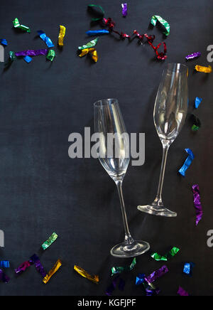 Zwei Sektgläser auf schwarzem Hintergrund mit buntem Konfetti. Party und Feier Konzept Stockfoto