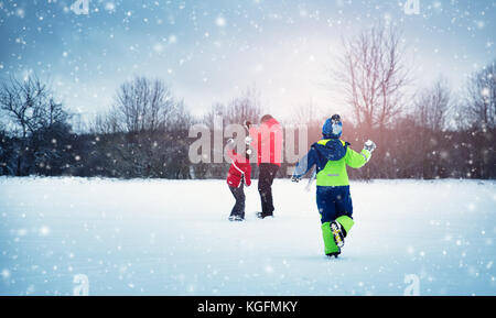 Vater mit Söhnen gehen bei Schneefall Stockfoto